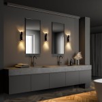 Lagos kinkiet 2xG9 w kolorze czarnym i złotym, zamontowany po bokach dwóch luster w nowoczesnej łazience. Kinkiet emituje ciepłe światło, podkreślając minimalistyczny design mebli oraz betonowy zlew. Tło w odcieniach szarości.