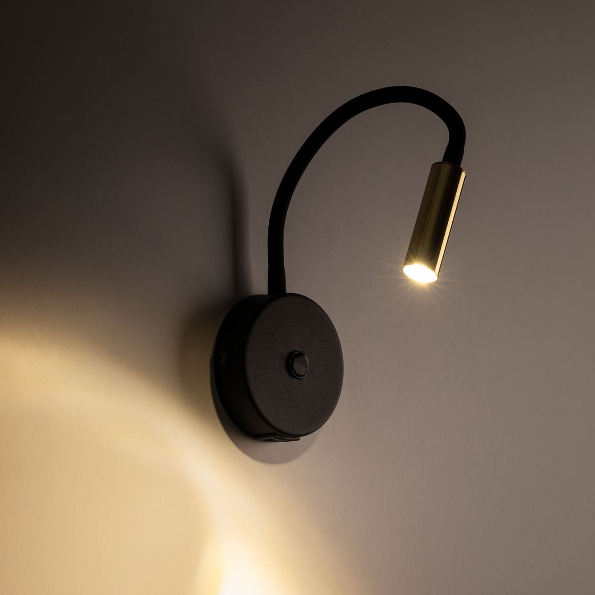 Lagos kinkiet z gniazdem USB, czarny z złotym akcentem. Lampa ma elastyczny, wygięty ramion, z metalowym kloszem. Montowana na ścianie, z widocznym przyciskiem na podstawie. Oświetlenie skierowane na ścianę, w neutralnym tle.