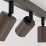 Brązowa lampa sufitowa typu spot z czterema oprawami na żarówki GU10. Ujęcie z bliska, ukazujące cylindryczne klosze umocowane na metalowej ramie. Klosze mają matowe wykończenie, a mocowania są w kolorze czarnym.