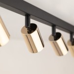 Czarna lampa sufitowa typu spot z ośmioma oprawami GU10. Złote, cylindryczne klosze zawieszone na prostokątnej, czarnej ramie. Ujęcie z bliska, pokazujące detale wykończenia i połączenia. Idealna do nowoczesnych wnętrz.