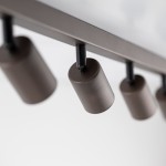 Brązowa lampa sufitowa typu spot z ośmioma oprawami na żarówki GU10. Ujęcie zbliżeniowe pokazuje cylindryczne klosze zamocowane na metalowej konstrukcji z czarnymi elementami mocującymi. Tło jasne, proste.
