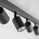 Czarna lampa sufitowa typu spot z osiemnastoma gniazdami GU10. Ujęcie z dołu, pokazujące detale cylindrycznych kloszy oraz metalowej konstrukcji. Lampa zamontowana na białym suficie, z widocznymi źródłami światła.