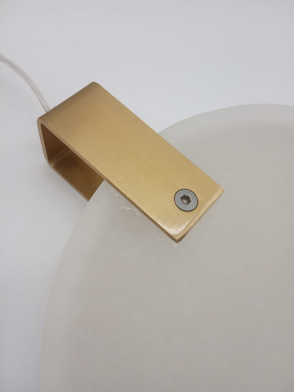 Lampa wisząca Marble D30 z mosiężnym uchwytem i białym kloszem z materiału imitującego marmur. Uchwyty w kolorze złotym, widoczna śruba mocująca. Produkt zawiera 1x LED/12W. Ujęcie z góry, na białym tle.