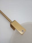 Lampa wisząca Marble D30 z mosiężnym uchwytem, zbliżenie na detal mocowania. Widoczna okrągła, mleczna klosz i prostokątny, złoty element. Tło białe, minimalistyczne, podkreślające elegancję lampy.
