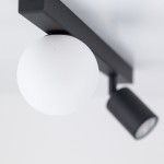 Czarna lampa sufitowa Vox z jednym źródłem światła GU10 i jednym G9. Okrągła, matowa kula w białym kolorze oraz prostokątny, czarny uchwyt. Ujęcie z góry, ukazujące detale konstrukcji.