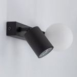 Vox kinkiet w kolorze czarnym z jedną oprawą na żarówkę GU10 i jedną na G9. Lampa ma cylindryczny klosz oraz okrągłą, matową kulę. Ujęcie z boku, montaż na ścianie, na jasnym tle.