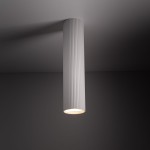 Lampa sufitowa Tune L w kolorze białym, o cylindrycznym kształcie z rowkowaną fakturą. Zawiera jedno gniazdo GU10. Ujęcie z dołu, pokazujące lampę wiszącą z otwartym źródłem światła, na ciemnym tle.