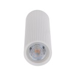 Lampa sufitowa Tune M, biała, z oprawą w kształcie cylindrycznym z rowkami. Zainstalowane źródło światła GU10 jest widoczne na dole. Umiejscowiona w pozycji pionowej, na jednolitym tle. Idealna do nowoczesnych wnętrz.