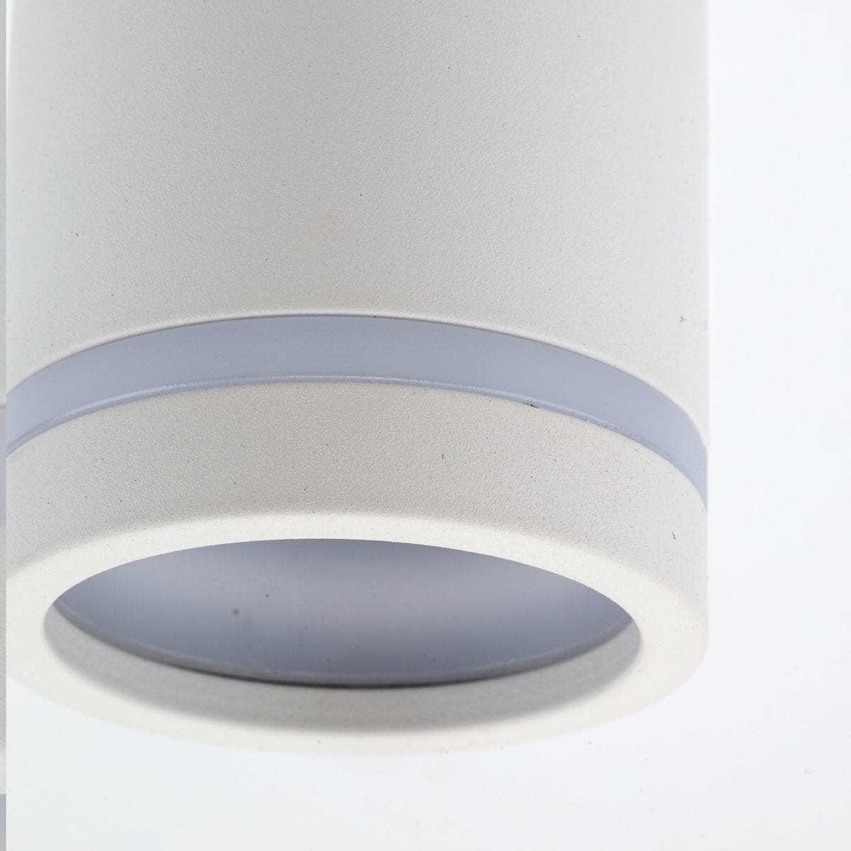 Biała lampa sufitowa Jet z oprawą na jedną żarówkę GU10. Okrągła konstrukcja z matowego materiału, z widocznym szklanym kloszem, w dolnej części z delikatnym, niebieskim akcentem. Ujęcie z bliska, ukazujące detale wykończenia.