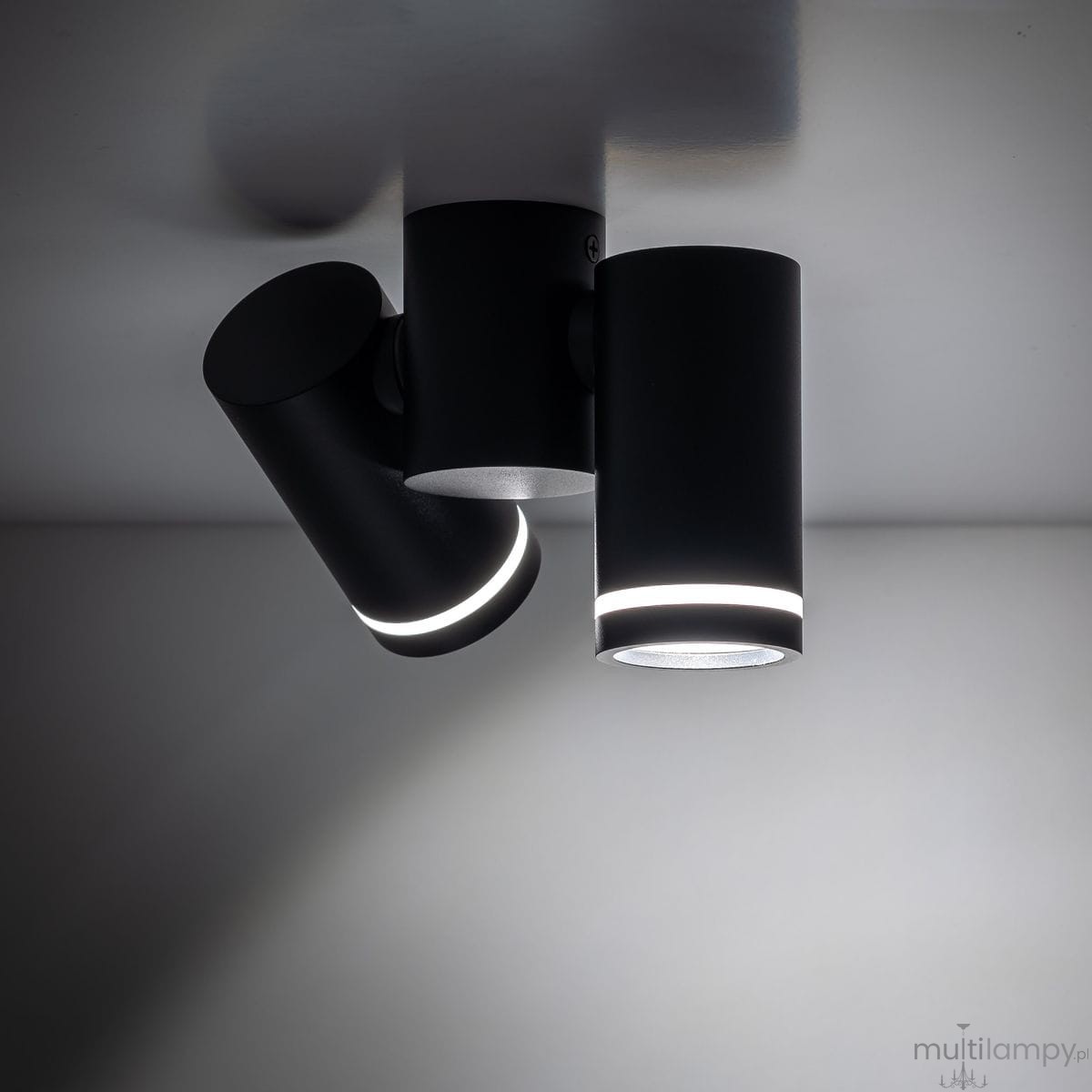Czarna lampa sufitowa Jet z dwoma punktami świetlnymi GU10. Cylindryczny kształt, z lekkim podświetleniem u dołu. Ujęcie z góry, widoczne dwa ruchome reflektory, montowane na suficie. Prosta, nowoczesna forma.