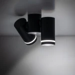 Czarna lampa sufitowa Jet z dwoma punktami świetlnymi GU10. Cylindryczny kształt, z lekkim podświetleniem u dołu. Ujęcie z góry, widoczne dwa ruchome reflektory, montowane na suficie. Prosta, nowoczesna forma.