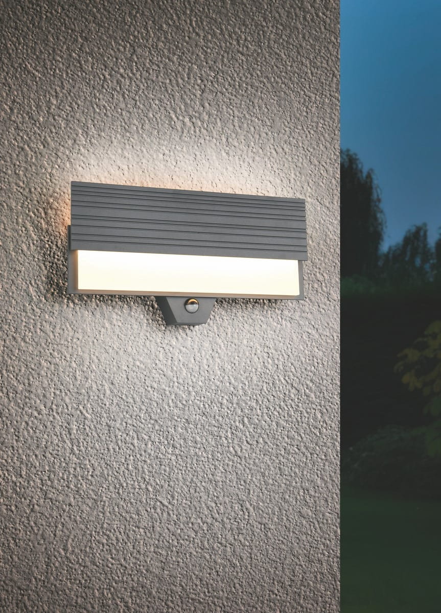 Kinkiet zewnętrzny Mariza w kolorze antracytowym z czujnikiem ruchu. Prostokątna lampa z fakturowaną górną częścią i mlecznym kloszem, zamontowana na ścianie, emitująca jasne światło. Idealna do oświetlenia przestrzeni zewnętrznych.
