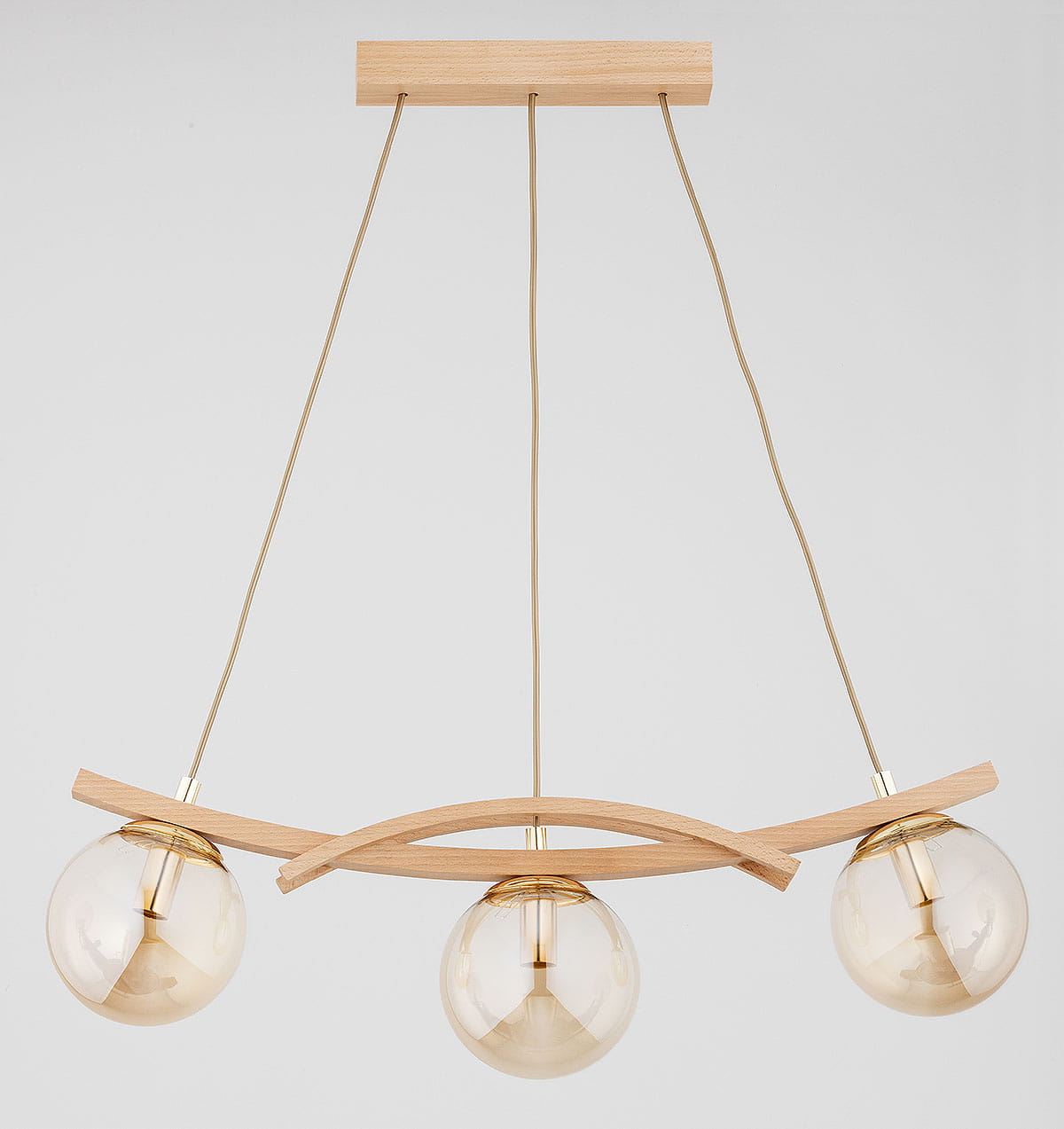 Lampa wisząca Sana z trzema oprawami na żarówki E14, z drewna w naturalnym kolorze i złotymi akcentami. Zawieszona na cienkich kablach, z półkulistymi kloszami w kolorze przezroczystym, z minimalistycznym drewnianym elementem dekoracyjnym.