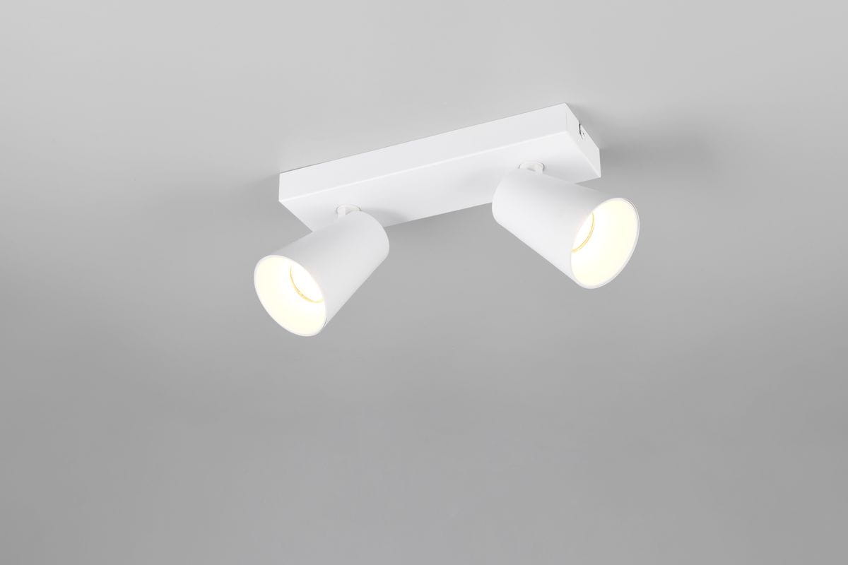 Biała lampa sufitowa Sharp z dwoma spotami GU10, zamontowana na prostokątnej podstawie. Kąt ujęcia z dołu, pokazujący lekko zaokrąglone klosze oraz źródła światła. Tło w jasnoszarym odcieniu, minimalistyczne.