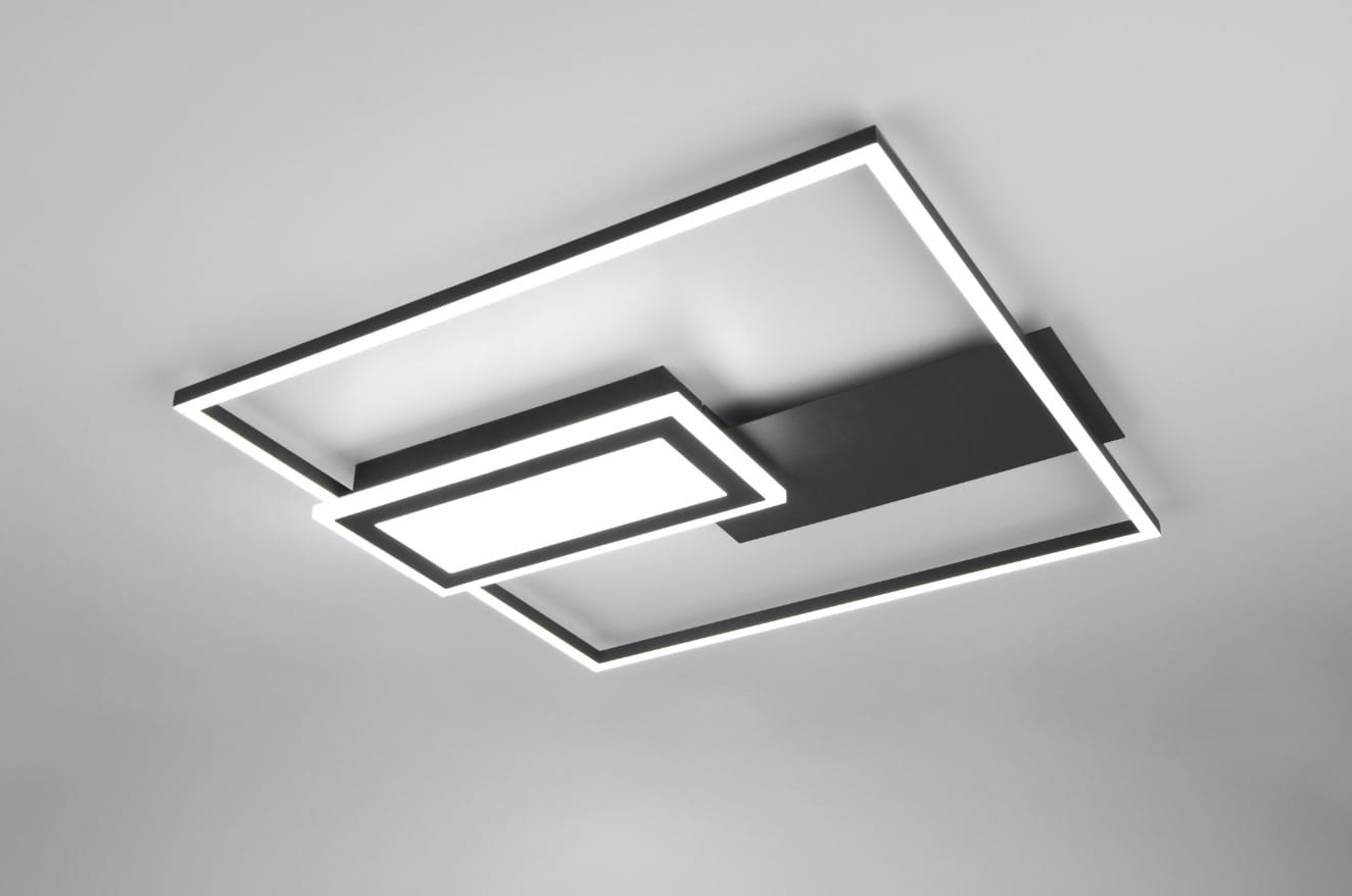 Czarna lampa sufitowa Spiro z pilotem, z dwiema diodami LED o mocy 32W. Kształt prostokątny z podświetleniem, zamontowana na suficie. Widoczny kontrast między czernią a białym światłem. Ujęcie z dołu, ukazujące detale i wykończenie.