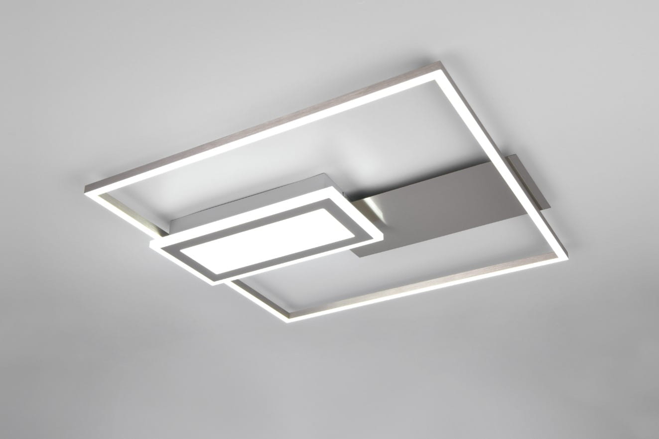 Lampa sufitowa Spiro w kolorze niklu, z dwiema diodami LED o mocy 32W. Posiada nowoczesny, geometryczny kształt z centralnym panelem i prostokątną ramą. Ujęcie z dołu, montowana na suficie, z pilotem do zdalnego sterowania.