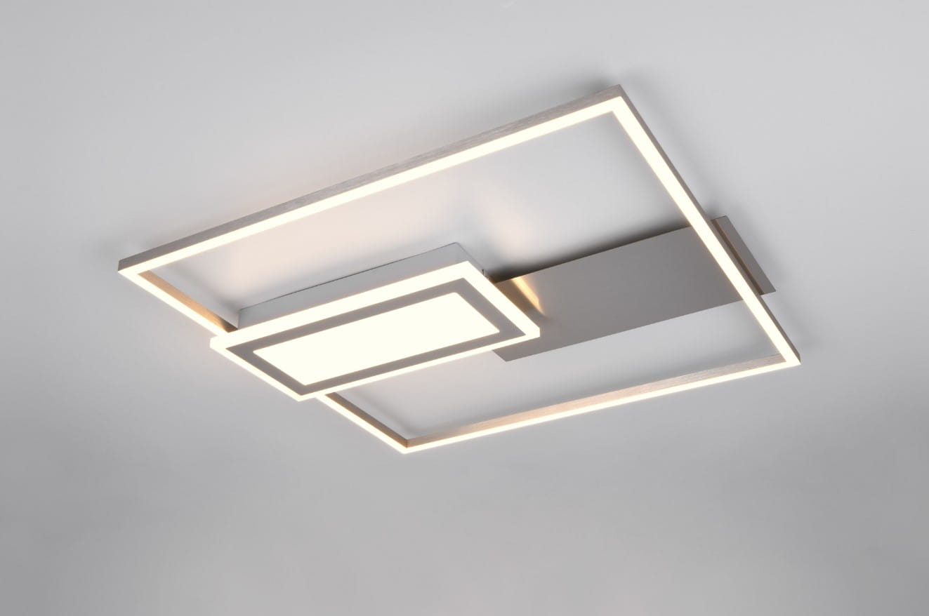 Lampa sufitowa Spiro w kolorze niklowym, o kwadratowym kształcie, z dwoma źródłami LED (32W). Posiada nowoczesny design z podświetlanym panelem i prostokątnymi ramkami. Ujęcie z dołu, pokazujące montaż na suficie.