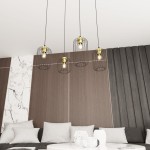 Lampa wisząca Vander 4 z czarnymi metalowymi kloszami w złotych detalach, zawieszona na długich linkach. Widoczne cztery żarówki w siatkach, umieszczona w nowoczesnym wnętrzu z drewnianą i marmurową ścianą oraz jasnymi poduszkami na kanapie.