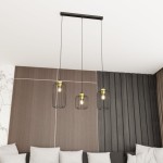 Lampa wisząca Vander 3GL z czarnymi metalowymi kloszami i złotymi detalami, zawieszona na trzech linkach. Wisi na prostokątnej podstawie, w tle widoczne drewniane panele i jasna kanapa z poduszkami.