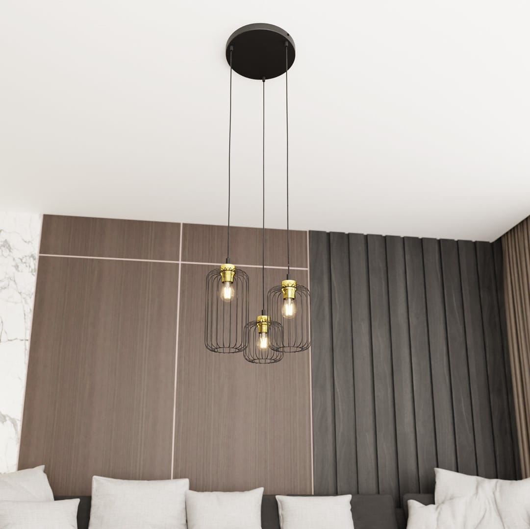 Lampa wisząca Vander 3 z trzema kloszami w czarnym metalowym wykończeniu i złotymi detalami. Zawieszona na dwóch cienkich linkach, wisi pod sufitem, w tle jasna ściana z tapetą i szarym obiciem sofy.