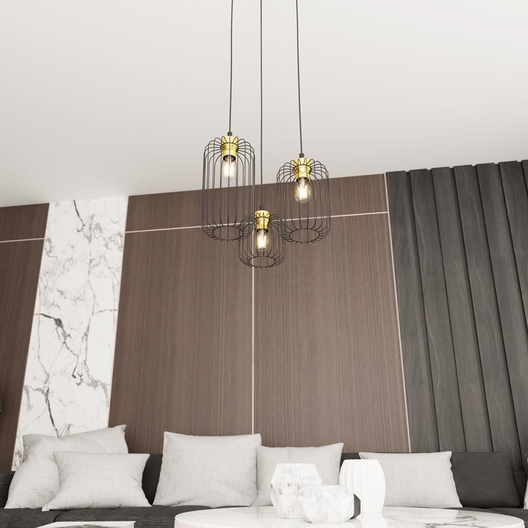 Lampa wisząca Vander 3, czarno-złota, z trzema kloszami w metalowej siatce, zawieszona na linach w nowoczesnym wnętrzu. Klosze eksponują żarówki E27, tworząc efektowne oświetlenie nad sofą w strefie wypoczynkowej.