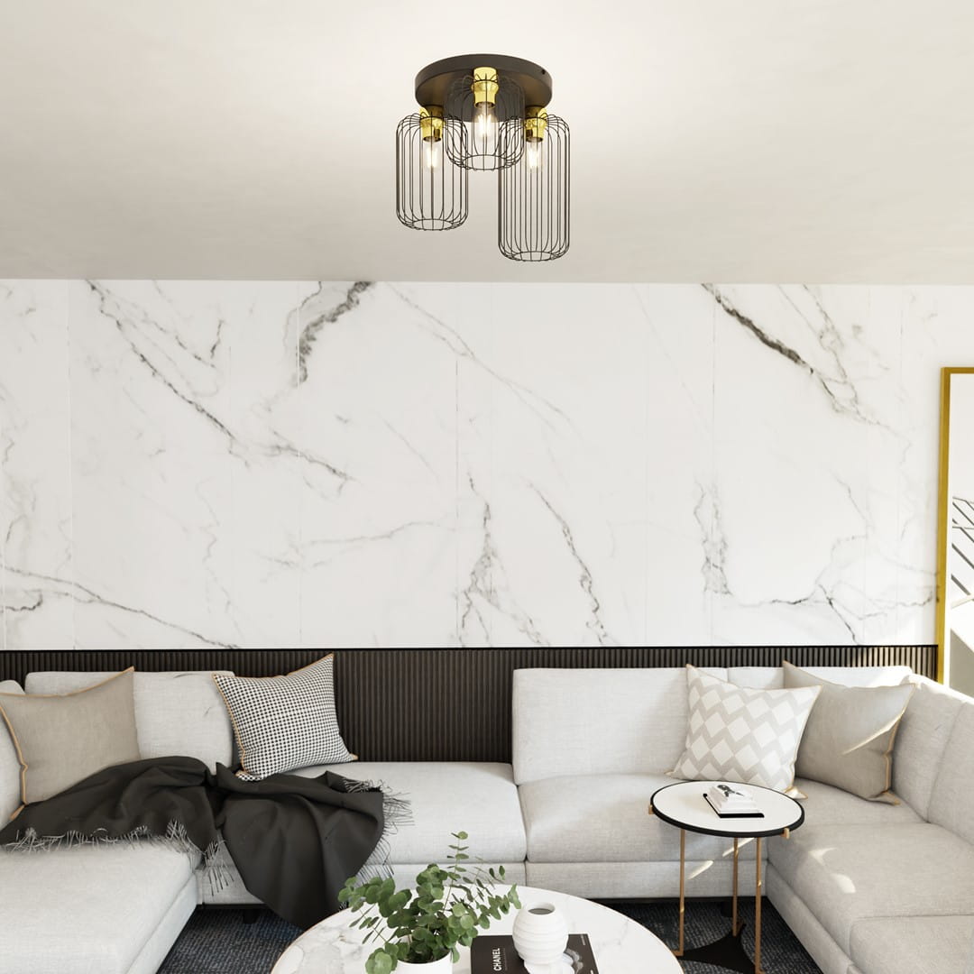 Czarna lampa sufitowa Barn 3GL z trzema źródłami światła E27, metalowa konstrukcja z dekoracyjnymi kloszami w złotym odcieniu, zamontowana na gładkim suficie, w nowoczesnym wnętrzu z jasną sofą i marmurową ścianą.