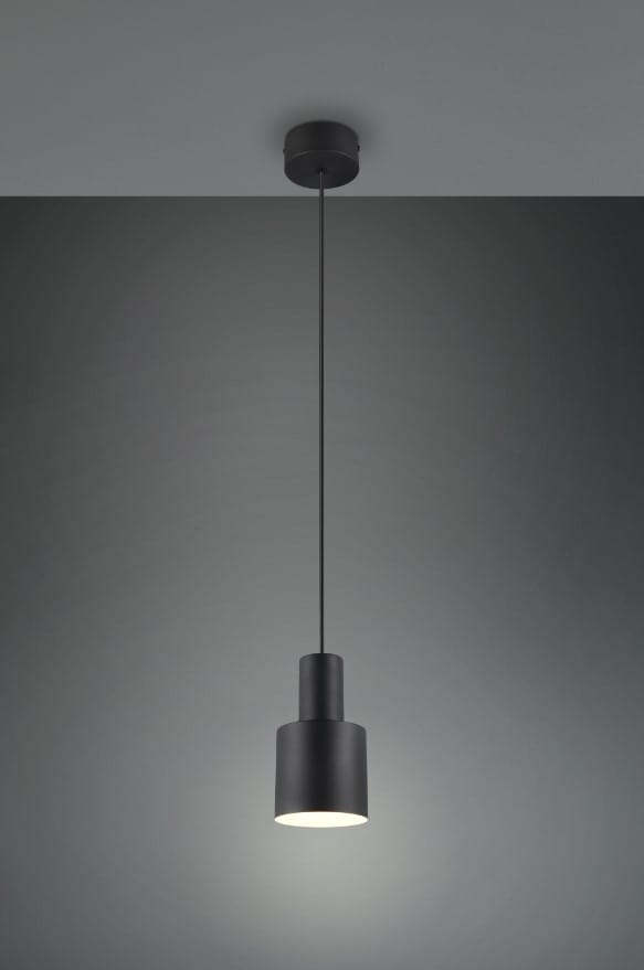 Czarna lampa wisząca Agudo z jednym gniazdem E27, o cylindrycznym kształcie. Zawieszona na cienkim przewodzie, z matową powierzchnią. Oświetlenie skierowane w dół, montowana do sufitu na jednolitym tle.