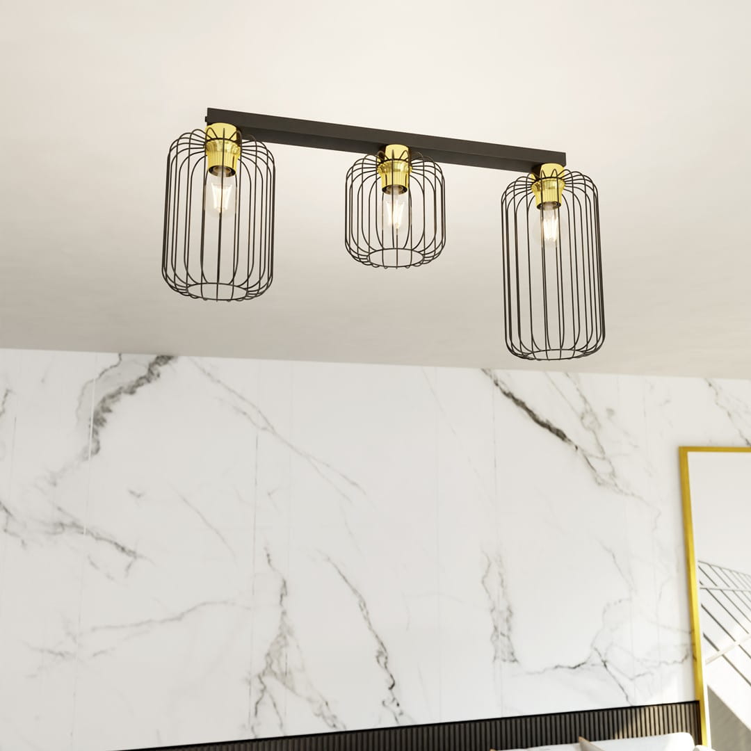 Lampa sufitowa Barn 3GL z trzema źródłami światła E27, zawieszona na czarnej metalowej belce. Klosze w formie siatkowych cylindrów z metalicznymi złotymi elementami. Tło z białego marmuru podkreśla elegancki design.
