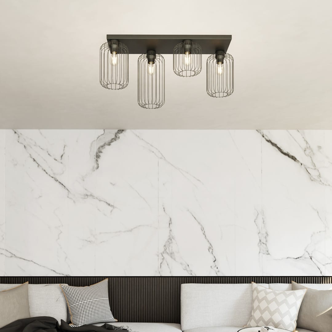 Lampa sufitowa Barn 4BL w kolorze czarnym, z czterema kloszami w formie siatki, montowana na prostokątnej podstawie. Widoczne żarówki E27. Umieszczona w nowoczesnym wnętrzu z marmurową ścianą i kanapą.