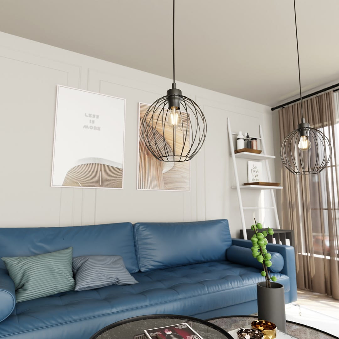 Lampa wisząca Nando 1BL z czarną metalową kloszem w kształcie kuli, zawieszona na cienkim przewodzie. Produkt znajduje się nad niebieską sofą, w tle plakaty oraz regał z drobnymi dekoracjami. Widać jedno źródło światła E27 wewnątrz klosza.