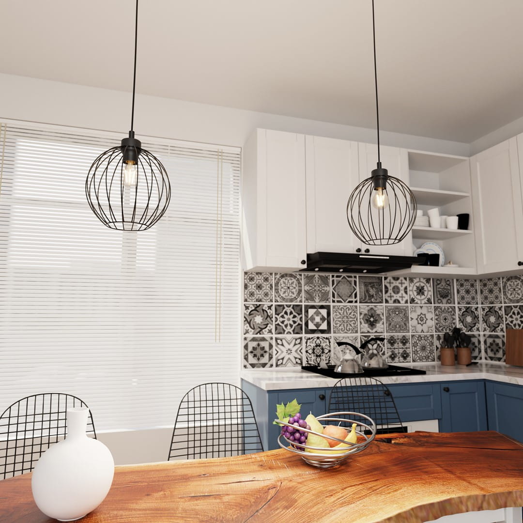 Lampa wisząca Nando 1BL w kolorze czarnym z kloszem w formie siatki. Zawieszona na długim kabelku w nowoczesnej kuchni, obok drewnianego stołu i kolorowej miski z owocami. Widoczny estetyczny kafelek w tle.