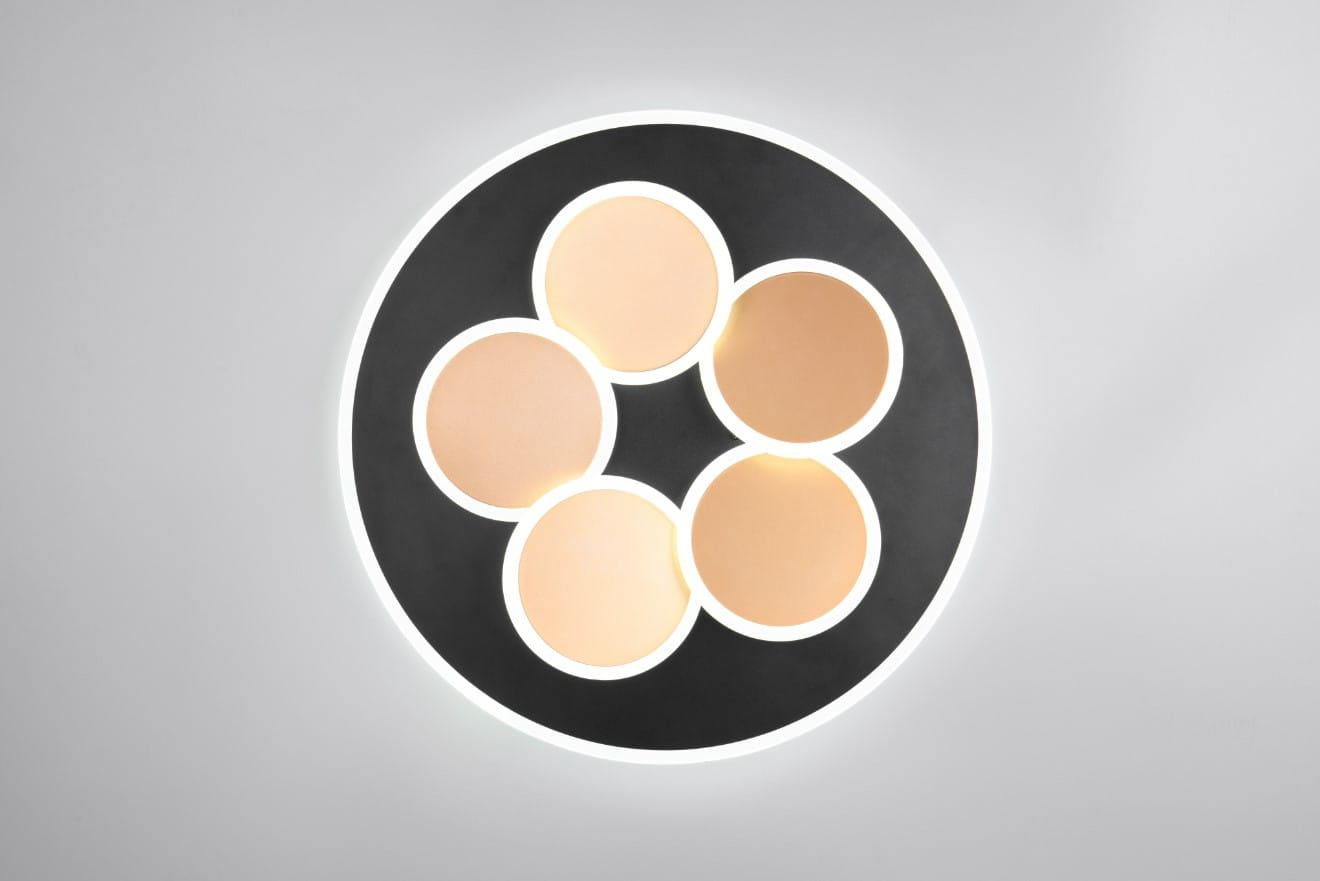 Mandala lampa sufitowa z pilotem, czarna i złota, z sześcioma okrągłymi lampami LED. Ujęcie z góry, pokazujące równomierne rozmieszczenie źródeł światła na okrągłej, matowej podstawie. Tło jasne, minimalistyczne.