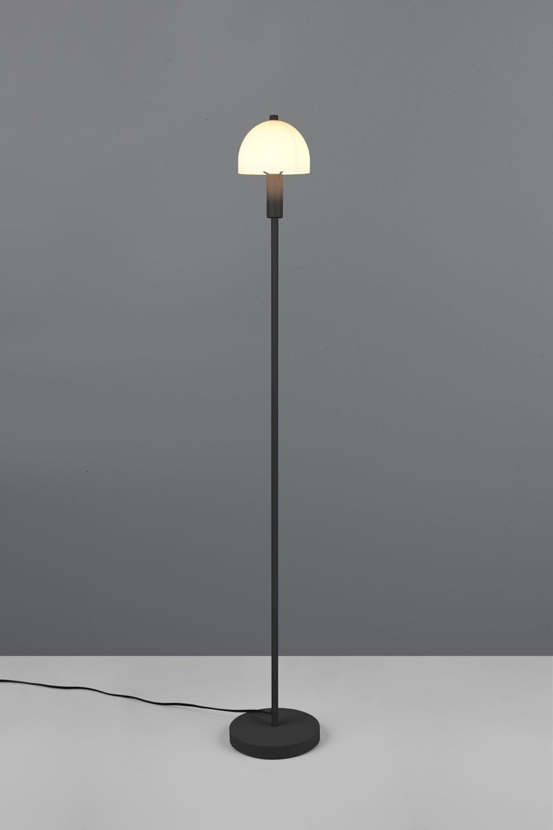 Czarna lampa podłogowa Glenn z jedną oprawą E14, z metalowym, prostym stelażem i okrągłą podstawą. Klasyczna klosz w kształcie półkuli, wykonany z białego materiału, umieszczony na górze, w pozycji stojącej. Kabel z wtyczką widoczny na podłodze.