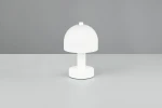 Biała lampa stołowa Glenn z kloszem w kształcie półkuli, na okrągłej podstawie. Ujęcie frontalne, produkt stoi na szarej powierzchni. Lampa przeznaczona na żarówkę E14.