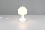 Biała lampa stołowa Glenn z kloszem w kształcie półkuli, umieszczona na okrągłej podstawie. Kable w białym kolorze, lampa o jednym gnieździe E14, zapalana, z lekkim świeceniem. Ujęcie frontalne na jednolitym tle.