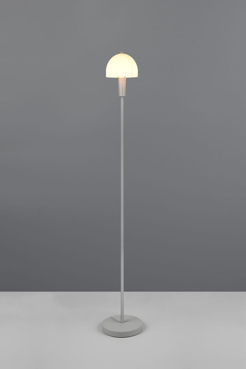 Lampa podłogowa Glenn w ciemnoszarym kolorze, z okrągłą podstawą i prostym, metalowym stelażem. Klosz w kształcie półkuli, wykonany z mlecznego szkła, umieszczony na górze. Ujęcie frontalne, na jednolitym tle.