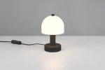 Lampa stołowa Glenn w kolorze czarnym z białym kloszem w kształcie półkuli. Ustawiona na płaskiej powierzchni, z widocznym przewodem z włącznikiem. Prosta, nowoczesna forma z okrągłą podstawą.