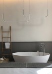 Czarna lampa wisząca Minima 120 z dwoma źródłami LED o mocy 40W, w minimalistycznym kształcie. Zawieszona na cienkich linkach, znajduje się nad białą wanną w nowoczesnej łazience, na tle szarej ściany. Detale: prosta forma, elegancki design.