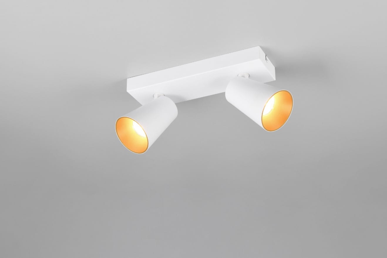 Biała lampa sufitowa typu spot z dwoma reflektorami GU10. Reflektory mają cylindryczny kształt, skierowane w różne strony, zamontowane na prostokątnej podstawie. Tło jest jasnoszare, co podkreśla minimalistyczny design.