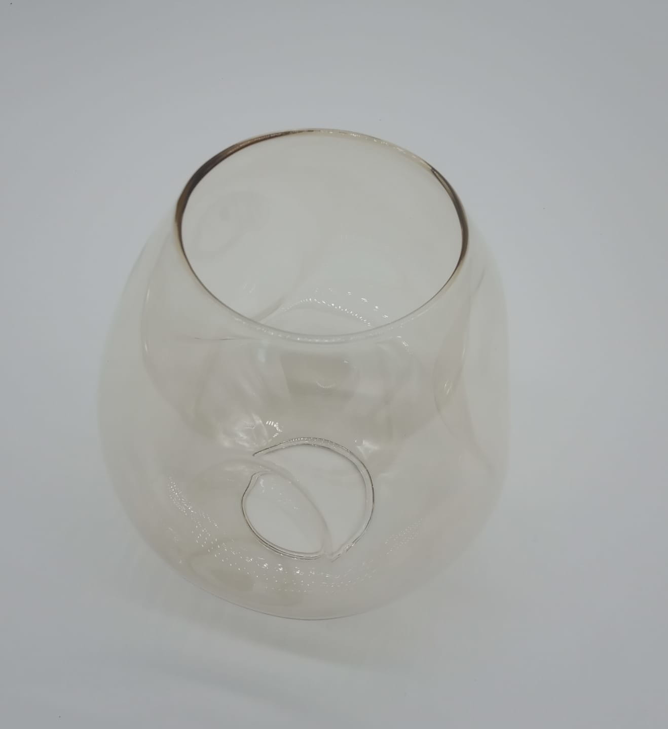 Przezroczysty klosz lampy wiszącej Modern Orchid w kształcie owalnym z wycięciem. Wykonany ze szkła, prezentuje bursztynowy odcień u góry. Ujęcie z góry, na białym tle, pokazujące szczegóły i gładką fakturę szkła.
