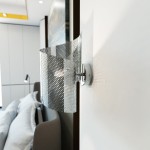 Kinkiet Spiral chrom 1xG9 w kolorze srebrnym, z unikalnym, perforowanym kloszem, zamontowany na ścianie. Produkt ma nowoczesny design i jest w pozycji pionowej, idealny do oświetlenia wnętrz. Tło stanowi jasna ściana.