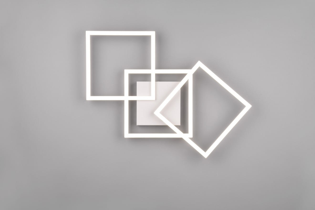 Biała lampa sufitowa Trail z trzema źródłami LED o mocy 31W, składająca się z trzech geometrycznych ram w różnych rozmiarach, umieszczonych na gładkiej szarej ścianie. Kształty obejmują kwadrat i romb, tworząc nowoczesny design.