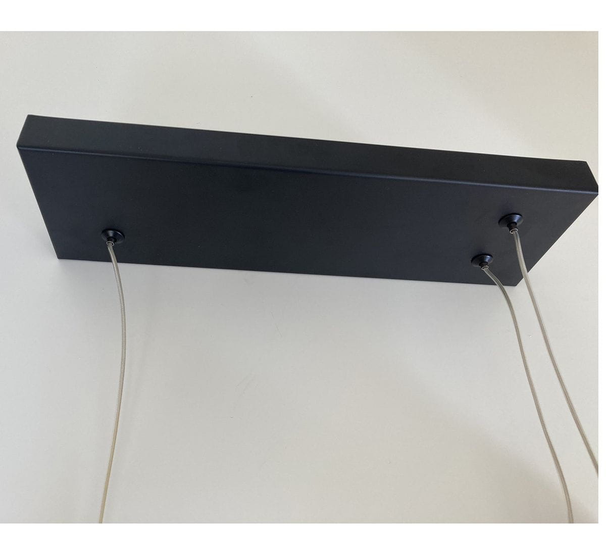 Lampa wisząca New Age w kolorze czarnym, z prostokątnym, matowym korpusem. Widoczne dwa przewody zawieszenia. Produkt z dwoma źródłami światła LED o mocy 40W. Ujęcie z dołu, ukazujące górną część lampy.