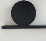 Lampa wisząca New Age w kolorze czarnym z dwiema oprawami LED. Okrągła, matowa forma z poziomą podstawą. Zawieszona pod kątem, na jednolitym tle. Idealna do nowoczesnych wnętrz.