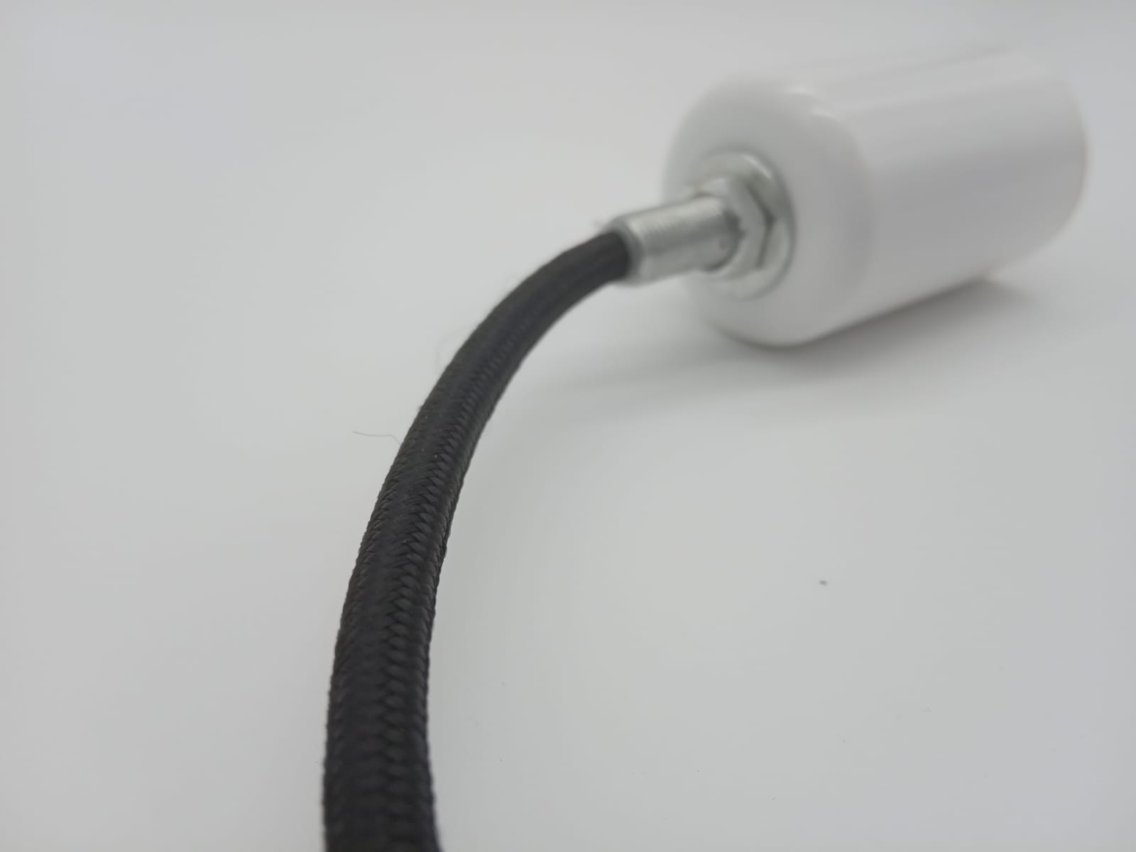 Lampa wisząca Nordic Woody z białym uchwytem E27 i czarnym, teksturowanym kablem, widoczna z boku. Uchwyt wykonany z ceramiki, a kabel ma solidne wykończenie. Tło proste, białe, co podkreśla detale lampy.