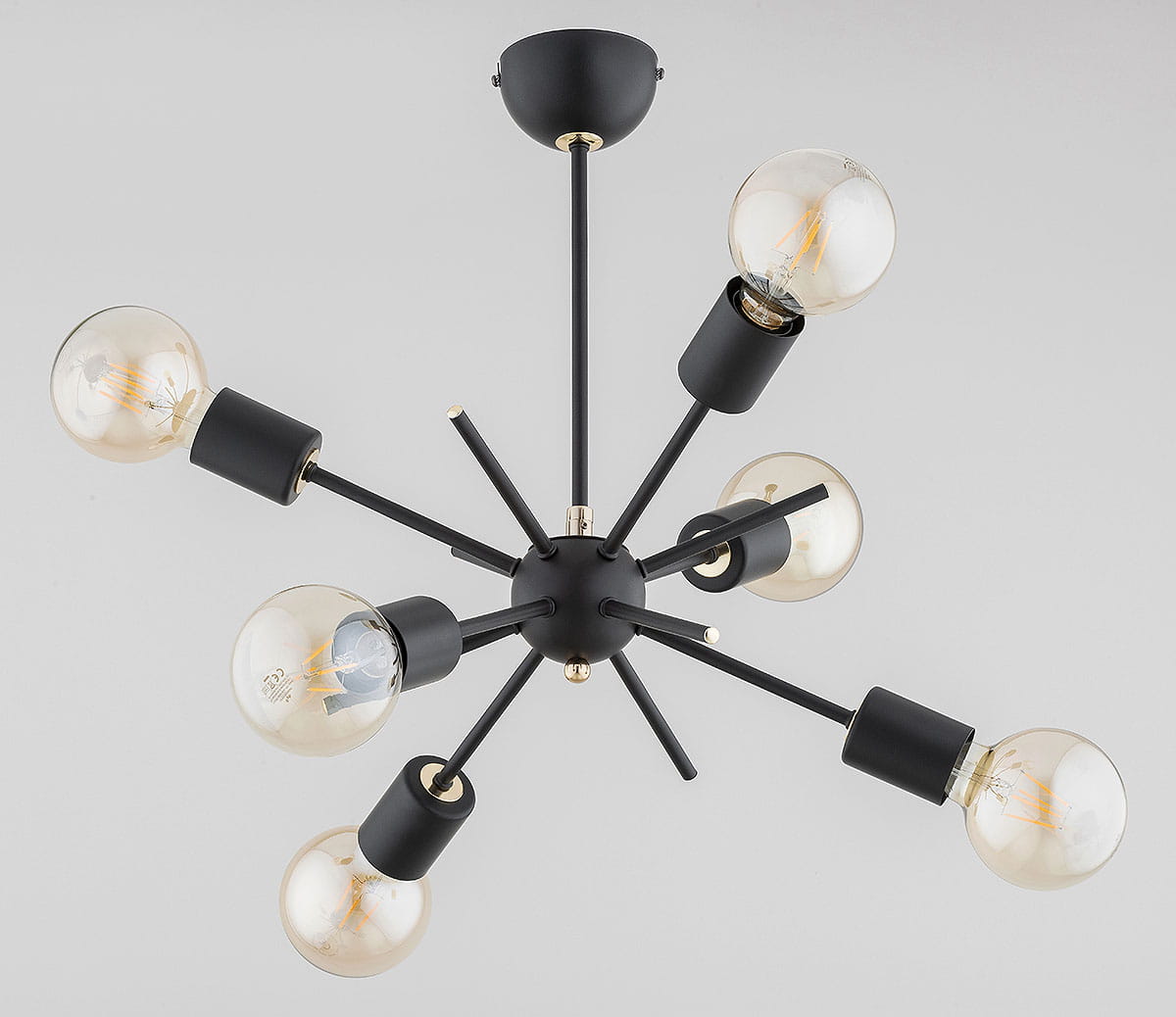 Lampa wisząca Igel, 6-punktowa, czarna. Okrągła podsufitka i sześć ramion z oprawkami w kształcie cylindrów. Widoczne żarówki w przezroczystych kloszach. Ujęcie z góry, prezentujące rozłożenie elementów.