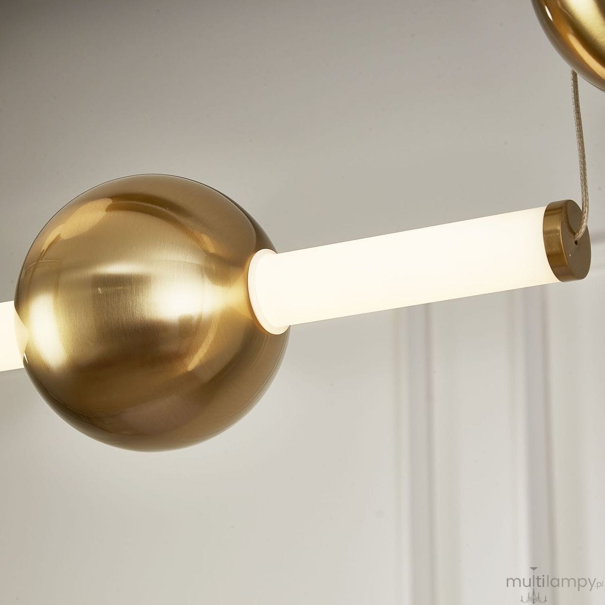 Lampa wisząca O-line S-4 w kolorze mosiądzu z czterema źródłami LED. Widoczna okrągła kula oraz prostokątny element świetlny. W komplecie z mocowaniem. Tło neutralne.