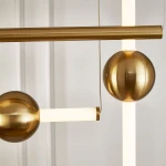 Lampa wisząca O-line S-4 z mosiądzu, z czterema źródłami LED. Widoczne elementy to mosiężne kule oraz prostokątne białe klosze. Produkt zawieszony na cienkim przewodzie, z oświetleniem w nowoczesnym stylu. Tło jasne, minimalistyczne.