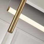 Lampa wisząca O-line L-4 w mosiężnym wykończeniu, z czterema źródłami LED, z prostokątnym kloszem w białym kolorze. Zbliżenie na metalowy element i klosz, zawieszony na cienkich linkach, na tle jasnej ściany.