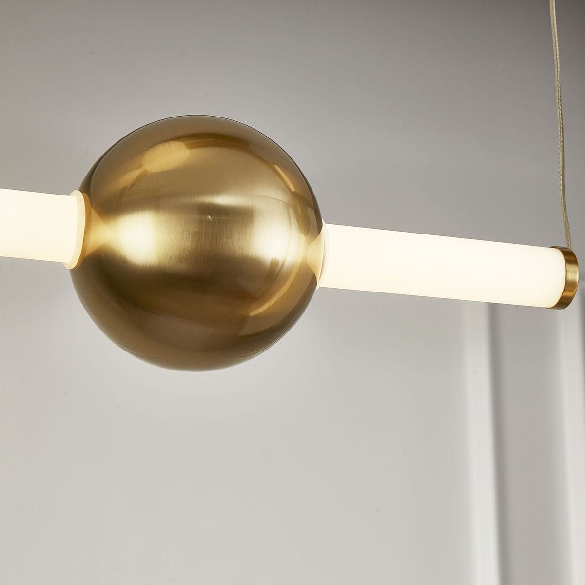 Lampa wisząca O-line L-4 w kolorze mosiądzu z okrągłą, błyszczącą kulą i dwoma prostokątnymi źródłami światła LED w białym kolorze. Produkt zawieszony na cienkim kablu, w nowoczesnym stylu, idealny do nowoczesnych wnętrz.